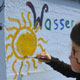Traminer Grundschülerinnen malen das Motto des Projektes an die Wand: Wasser ist Leben.